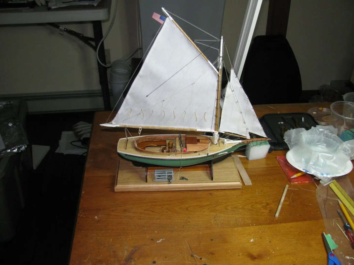 A wooden model of a sailboat on top of a table.