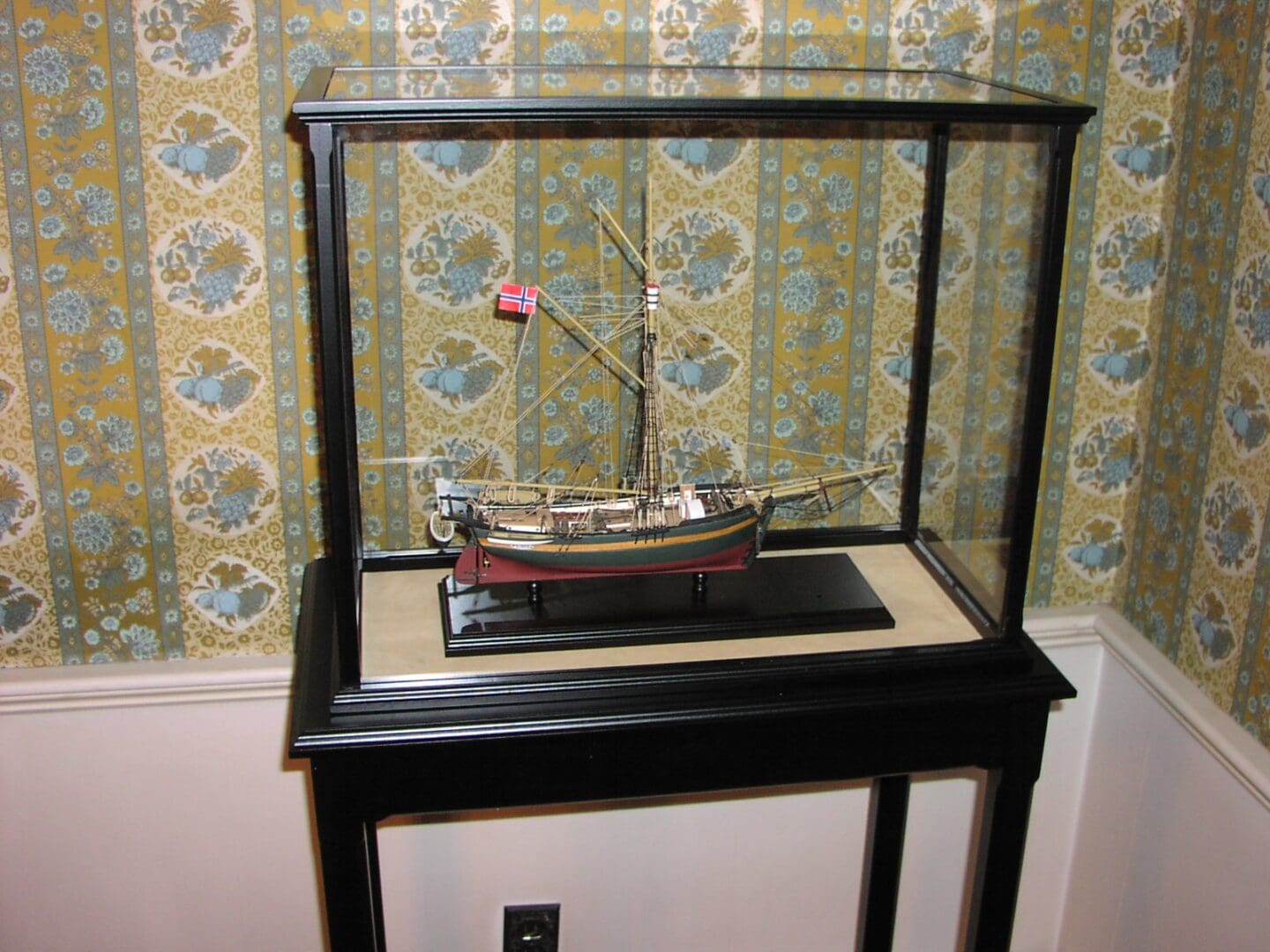 A small model boat on display in a glass case.